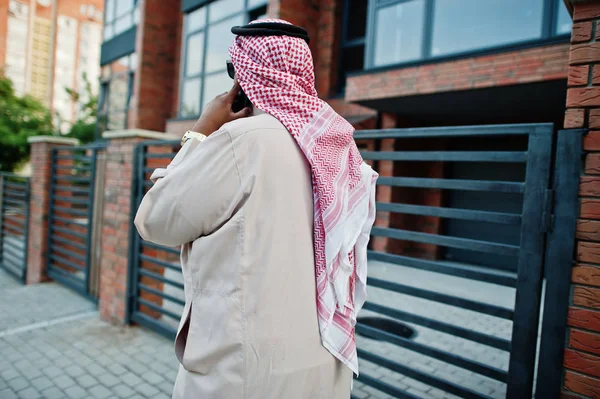Back of Middle Eastern arab business man posed on street speaking on mobile phone.