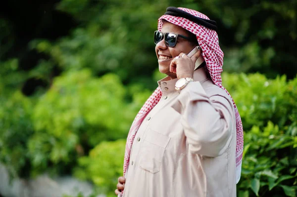 Güneş gözlüklü, sokakta poz Orta Doğu Arap iş adamı üstünde hareket eden telefon konuşma.