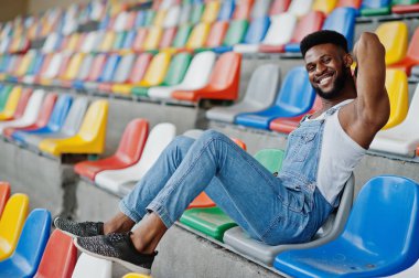 Kot Tulum, Afro-Amerikan yakışıklı Stadyumu'nda renkli sandalyeler üzerinde poz verdi. Şık siyah adam portresi.