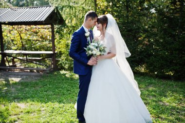 Mutlu yeni evli çift açık havada bahçe veya park ahşap gazebo yanındaki düğün gününde poz.