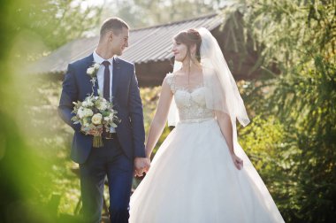 Mutlu yeni evli çift açık havada bahçe veya park ahşap gazebo yanındaki düğün gününde poz.