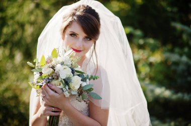 Güzel düğün buket onun elinde açık havada tutan bir nazik muhteşem gelin portresi.