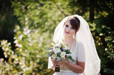 Güzel düğün buket onun elinde açık havada tutan bir nazik muhteşem gelin portresi.