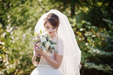 Güzel düğün buket onun elinde açık havada tutan bir nazik muhteşem gelin portresi.