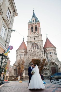 Yeni evli çift şehrin eski kilisede yanında güzel bir sonbahar düğün gününde poz.
