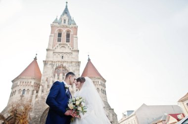 Yeni evli çift şehrin eski kilisede yanında güzel bir sonbahar düğün gününde poz.