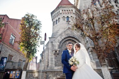 Yeni evli çift şehrin eski kilisede yanında güzel bir sonbahar düğün gününde poz.