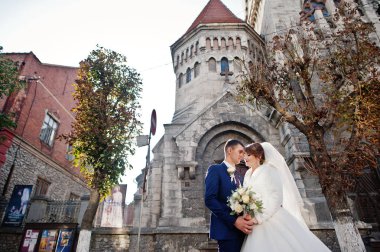 Yeni evli çift şehrin eski kilisede yanında güzel bir sonbahar düğün gününde poz.