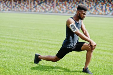 Spor stadyumunda germe egzersiz yaparak Afro-Amerikan erkek atlet.