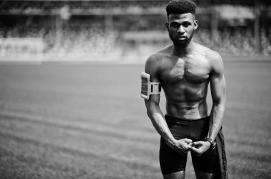 Afro-Amerikan erkek atlet seksi spor çıplak gövde erkek spor kol durumda cep telefonu, yeşil çim futbol Stadı poz için çalışan ile.