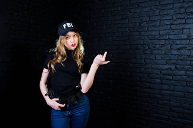 FBI kadın ajanı şapkalı ve karanlık duvara karşı stüdyoda silahla.