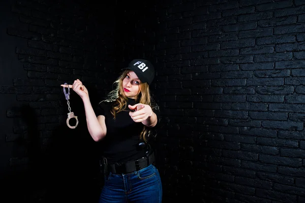 FBI kadın ajanı şapkalı ve karanlık duvara karşı stüdyoda silahla.