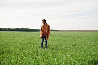 Şık adam gözlük, kahverengi ceket ve şapka yeşil sahada poz verdi..