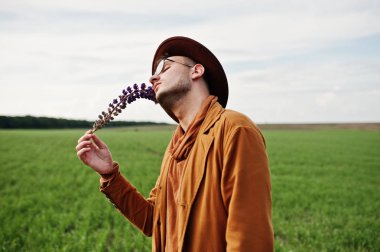 Şık adam gözlük, kahverengi ceket ve şapka yeşil sahada poz verdi..