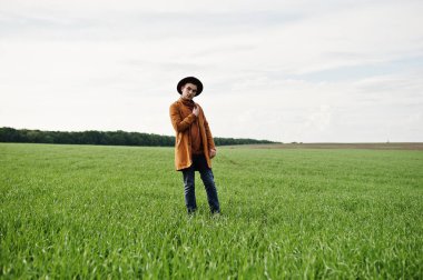 Şık adam gözlük, kahverengi ceket ve şapka yeşil sahada poz verdi..