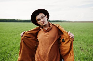 Şık adam gözlük, kahverengi ceket ve şapka yeşil sahada poz verdi..