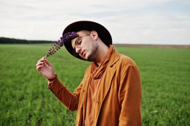 Şık adam gözlük, kahverengi ceket ve şapka yeşil sahada poz verdi..