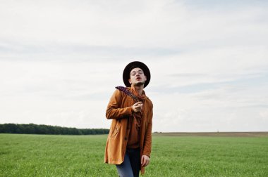 Şık adam gözlük, kahverengi ceket ve şapka yeşil sahada poz verdi..