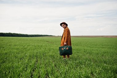 Gözlük, kahverengi ceket ve şapka çanta ile şık adam yeşil sahada poz verdi..
