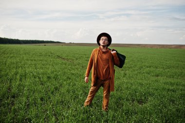 Gözlük, kahverengi ceket ve şapka çanta ile şık adam yeşil sahada poz verdi..