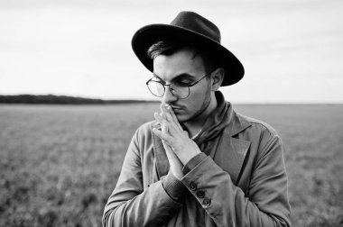 Şık adam gözlük, kahverengi ceket ve şapka yeşil sahada poz verdi..