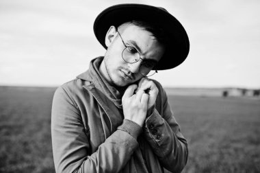 Şık adam gözlük, kahverengi ceket ve şapka yeşil sahada poz verdi..