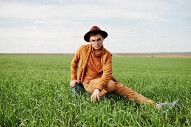 Gözlük, kahverengi ceket ve şapka çanta ile şık adam yeşil sahada poz verdi..