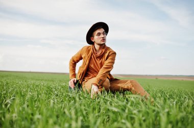 Gözlük, kahverengi ceket ve şapka çanta ile şık adam yeşil sahada poz verdi..