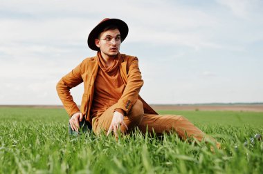 Gözlük, kahverengi ceket ve şapka çanta ile şık adam yeşil sahada poz verdi..