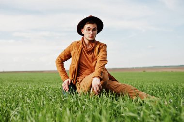 Gözlük, kahverengi ceket ve şapka çanta ile şık adam yeşil sahada poz verdi..