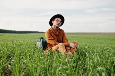 Gözlük, kahverengi ceket ve şapka çanta ile şık adam yeşil sahada poz verdi..