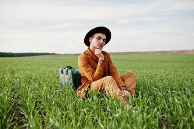 Gözlük, kahverengi ceket ve şapka çanta ile şık adam yeşil sahada poz verdi..