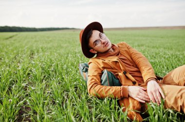 Gözlük, kahverengi ceket ve şapka çanta ile şık adam yeşil sahada poz verdi..