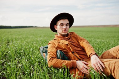 Gözlük, kahverengi ceket ve şapka çanta ile şık adam yeşil sahada poz verdi..