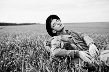 Gözlük, kahverengi ceket ve şapka çanta ile şık adam yeşil sahada poz verdi..