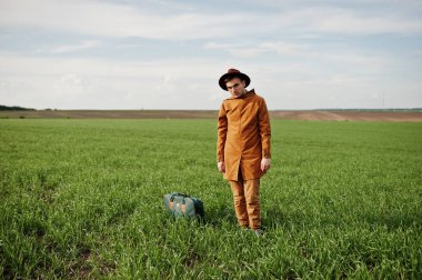 Gözlük, kahverengi ceket ve şapka çanta ile şık adam yeşil sahada poz verdi..