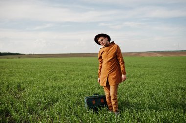 Gözlük, kahverengi ceket ve şapka çanta ile şık adam yeşil sahada poz verdi..