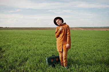 Gözlük, kahverengi ceket ve şapka çanta ile şık adam yeşil sahada poz verdi..