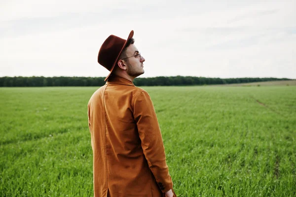 Şık adam gözlük, kahverengi ceket ve şapka yeşil sahada poz verdi..