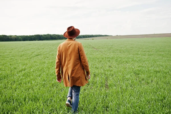 Şık adam gözlük, kahverengi ceket ve şapka yeşil sahada poz verdi..
