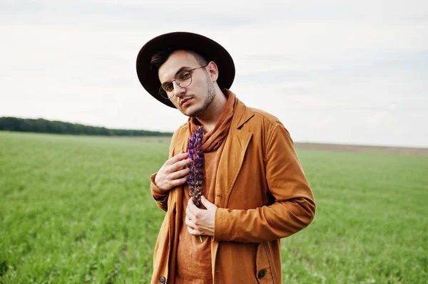 Şık adam gözlük, kahverengi ceket ve şapka yeşil sahada poz verdi..