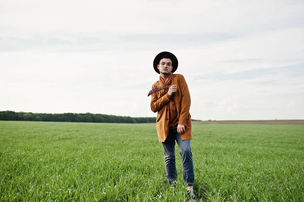 Şık adam gözlük, kahverengi ceket ve şapka yeşil sahada poz verdi..