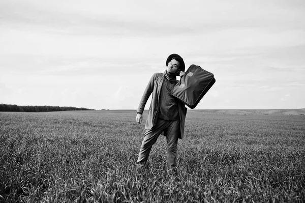 Gözlük, kahverengi ceket ve şapka çanta ile şık adam yeşil sahada poz verdi..