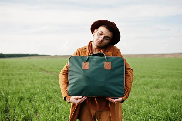Gözlük, kahverengi ceket ve şapka çanta ile şık adam yeşil sahada poz verdi..