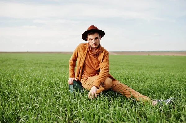 Gözlük, kahverengi ceket ve şapka çanta ile şık adam yeşil sahada poz verdi..