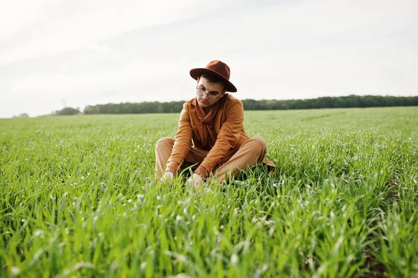 Gözlük, kahverengi ceket ve şapka çanta ile şık adam yeşil sahada poz verdi..