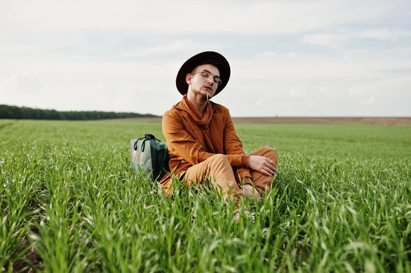 Gözlük, kahverengi ceket ve şapka çanta ile şık adam yeşil sahada poz verdi..
