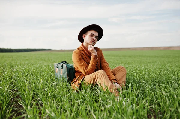 Gözlük, kahverengi ceket ve şapka çanta ile şık adam yeşil sahada poz verdi..