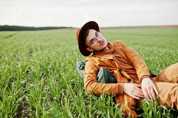Gözlük, kahverengi ceket ve şapka çanta ile şık adam yeşil sahada poz verdi..