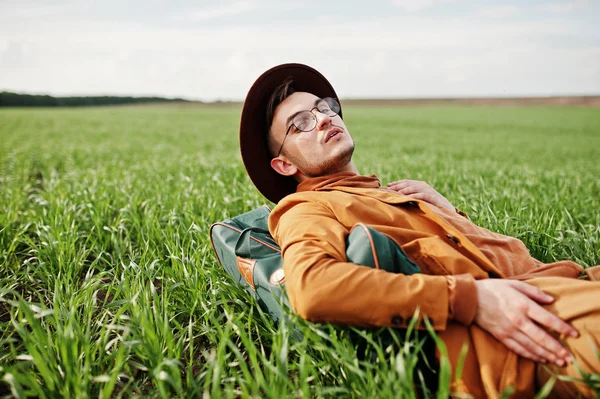 Gözlük, kahverengi ceket ve şapka çanta ile şık adam yeşil sahada poz verdi..